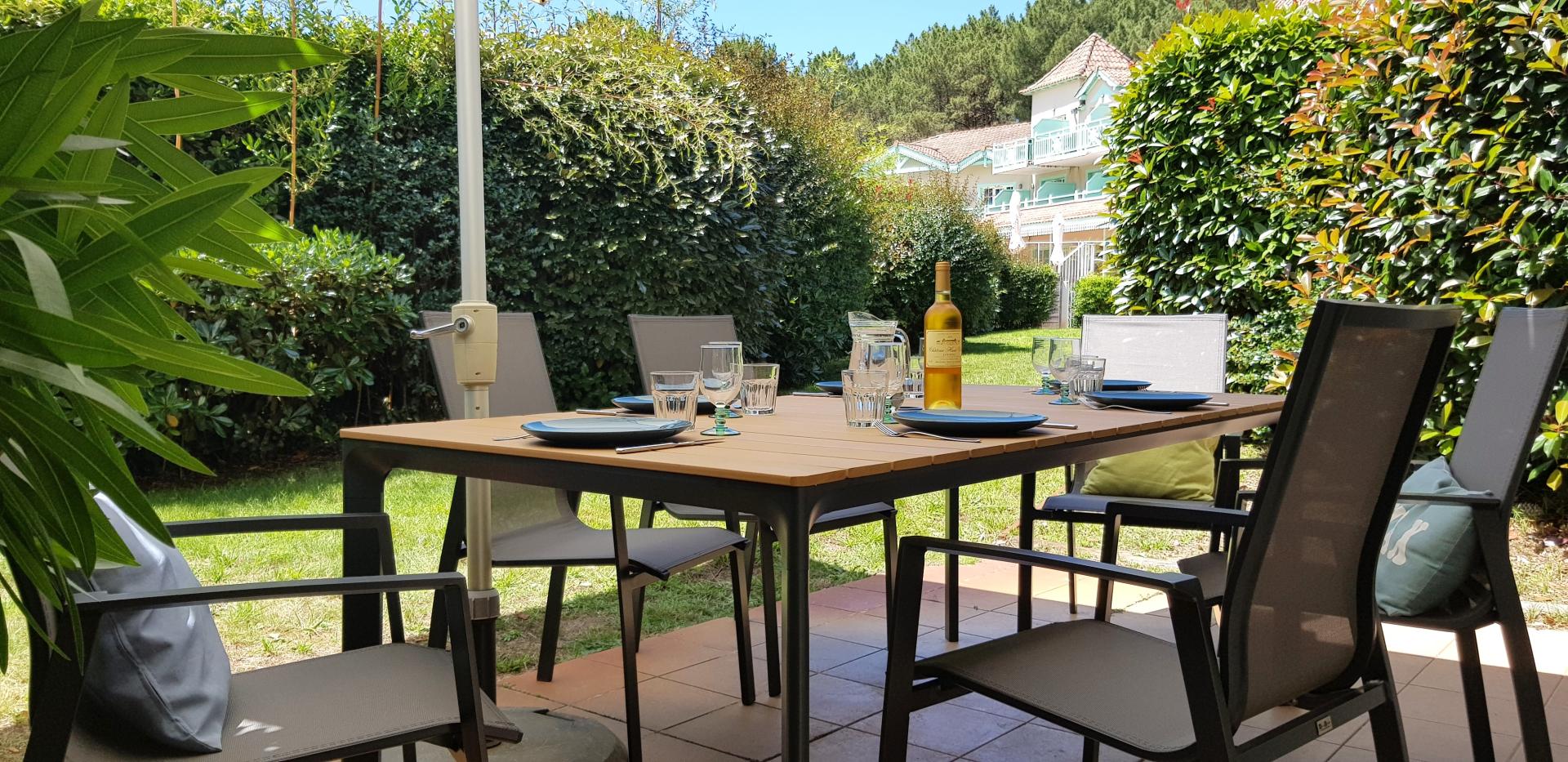 Table de jardin dressée sur la terrasse avec vue jardin