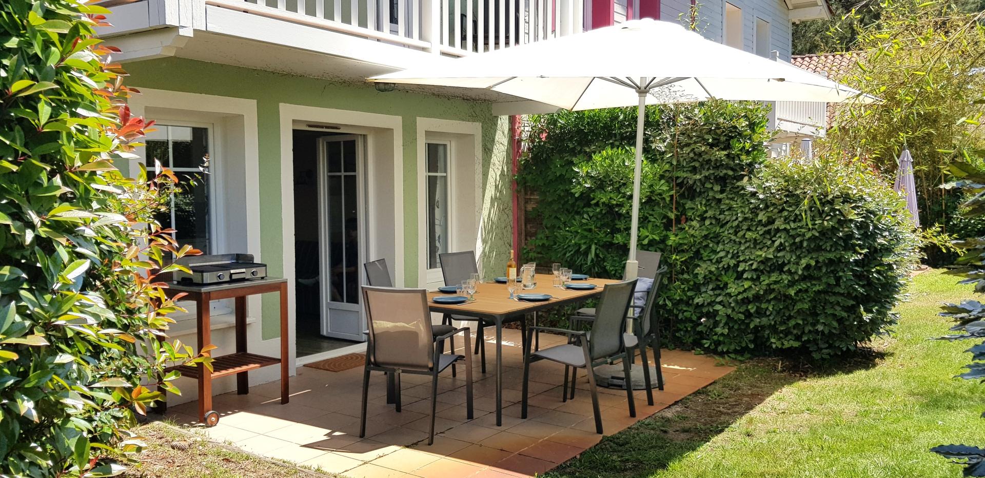 Terrasse ensoleillée avec salon de jardin et plancha