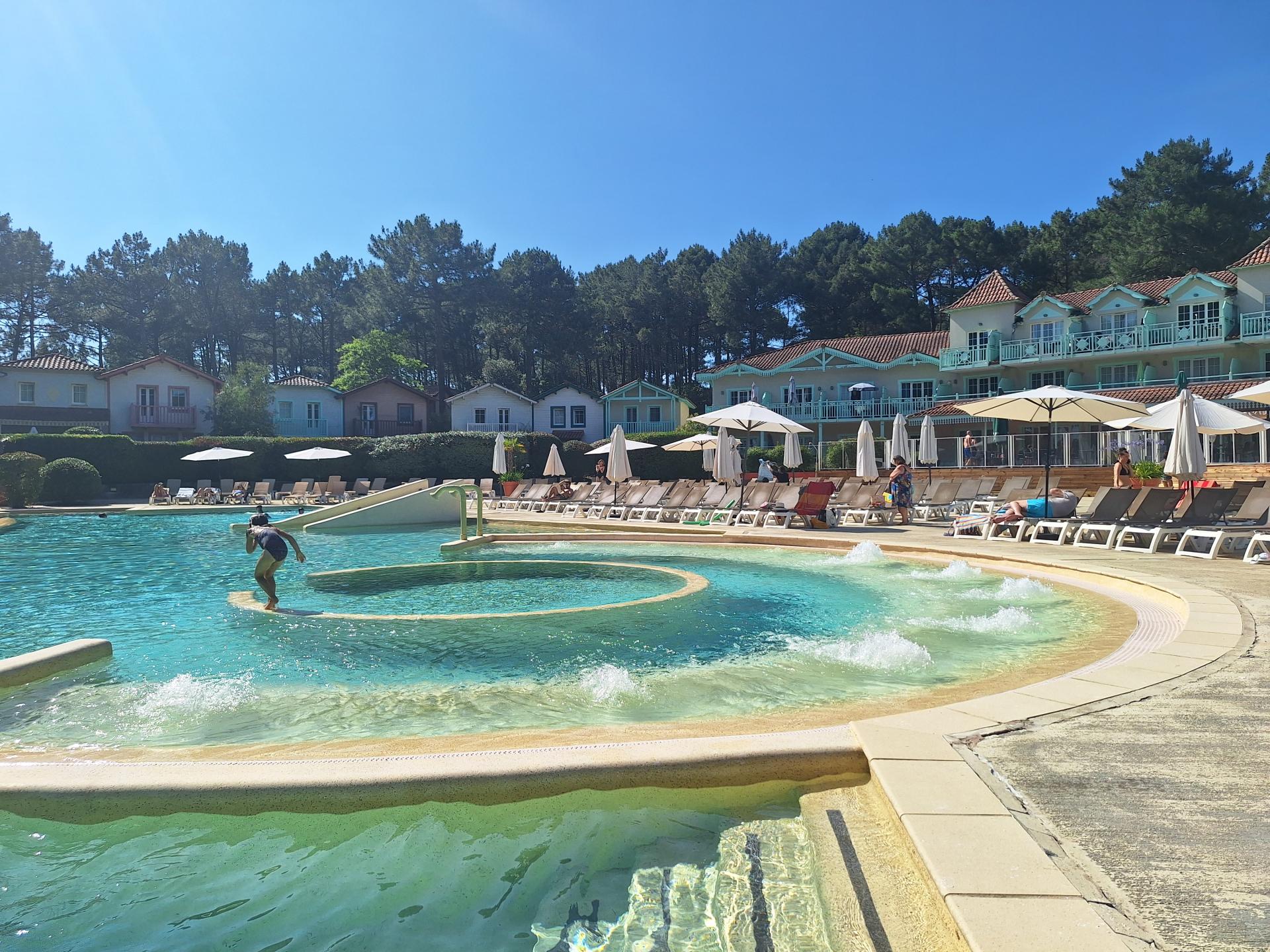 Grande piscine chauffée et bains à remous avec maisons et pins en arrière plan