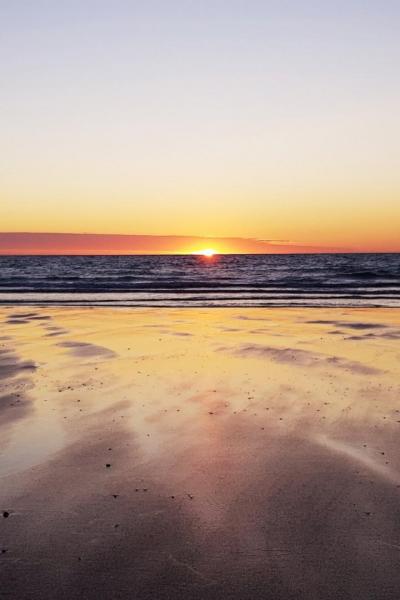 Réflexions du coucher de soleil sur le sable humide